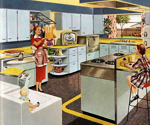 This 1953 advertisement for KitchenMaid cabinets shows a housewife delighting in the modern marvels of her kitchen. Via RetroRenovation.com.