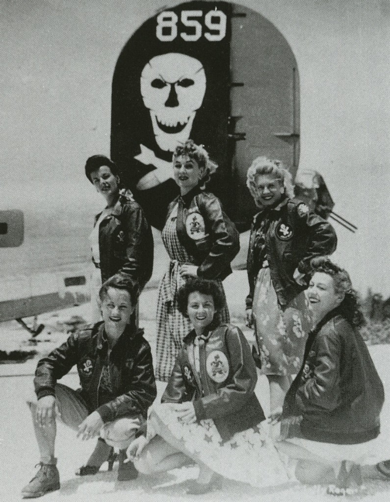 Six U.S.O. Girls wear A-2 jackets belonging to the 90th Bomb Group, a.k.a. "Jolly Rogers," under a B-24 bomber. From the collection of John Campbell.