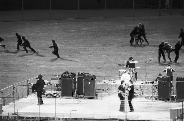 Police clear the field of fans as The Beatles perform in Candlestick Park, San Francisco, California, August 29, 1966. Photo: Bettmann/CORBIS.