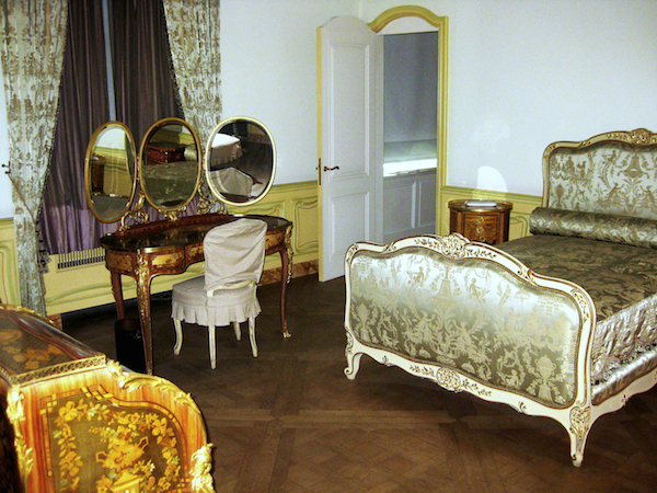A bedroom inside Huguette Clark's apartment. In the 1990s, Huguette Clark commissioned exact replicas of all her mother's Victorian bedroom furniture including a gray-painted and parcel-gilt bed upholstered in Chinoserie-patterned silk damask, a French ormolu-mounted tulipwood, bois satine, sycamore, and fruitwood marquetry and parquetry dressing table with three folding oval mirrors, and a French ormolu-mounted tulipwood, sycamore, and stained fruitwood marquetry and parquetry bureau a cylindre. (Via the estate of Huguette Clark from EmptyMansionsBook.com)